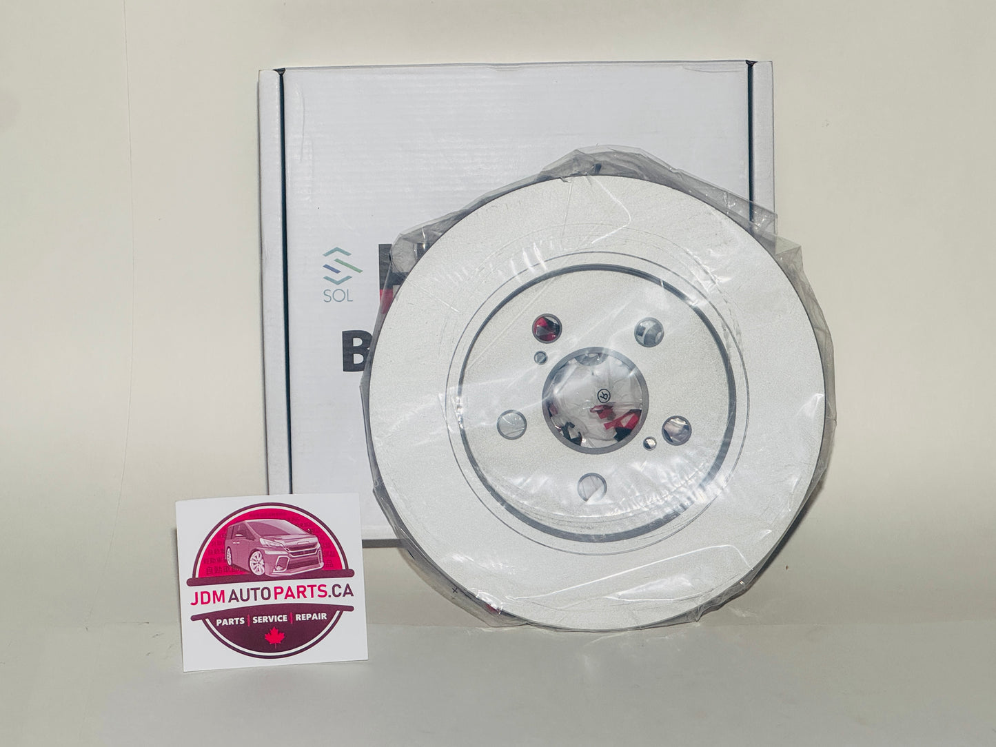 Car brake disc with packaging and JDM Auto Parts logo on a white background