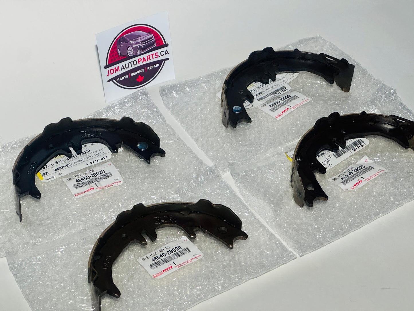Set of brake shoes on a white surface with JDM Auto Parts logo in the corner.
