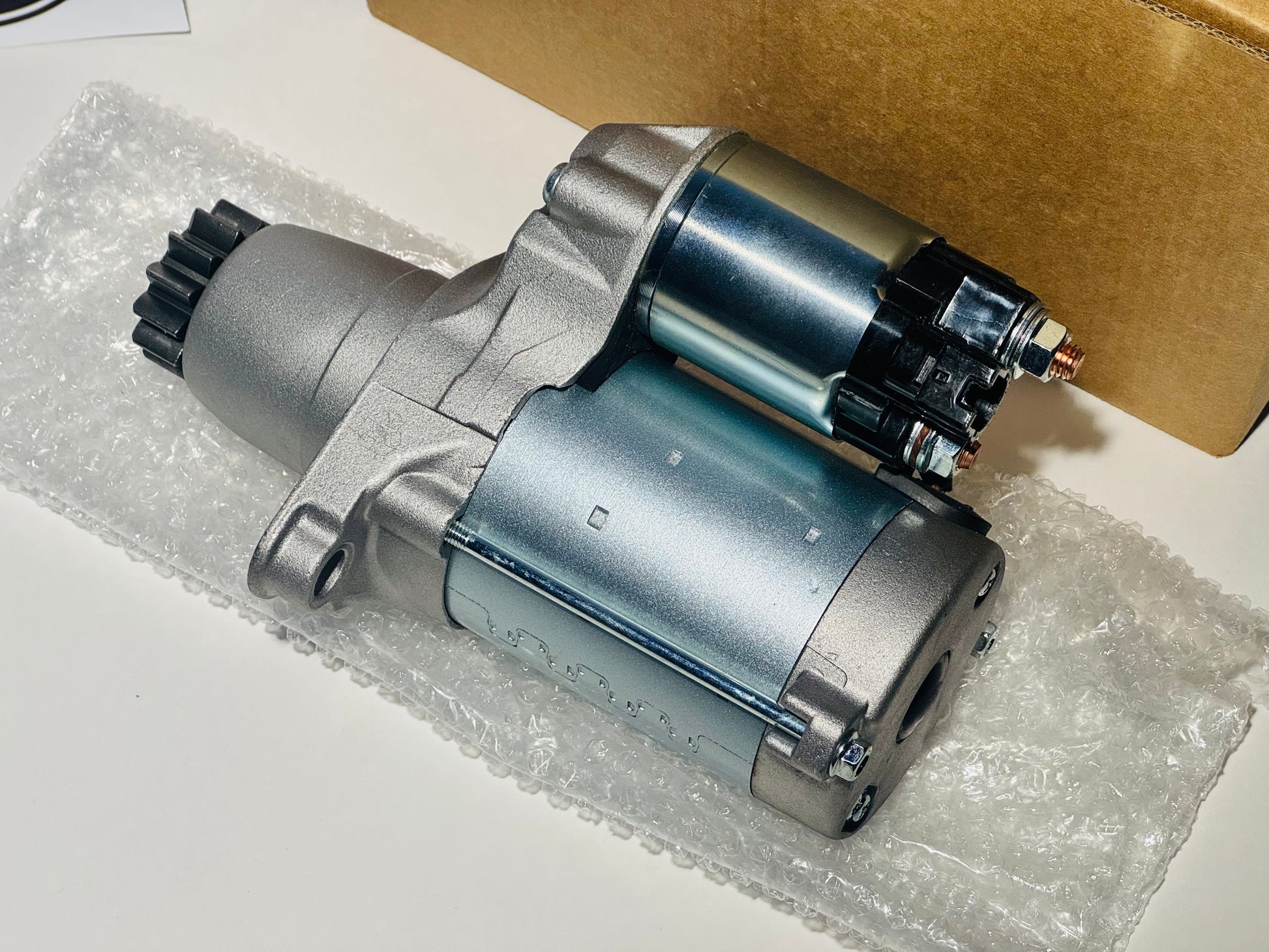 Car starter motor on a white surface with bubble wrap