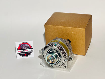 A Nissan Elgrand alternator is displayed in front of a cardboard box with a logo on the lower right corner. The alternator is made for 2002-2010 NISSAN ELGRAND ALTERNATOR ASSY E51 NE51 ME51 MNE51 