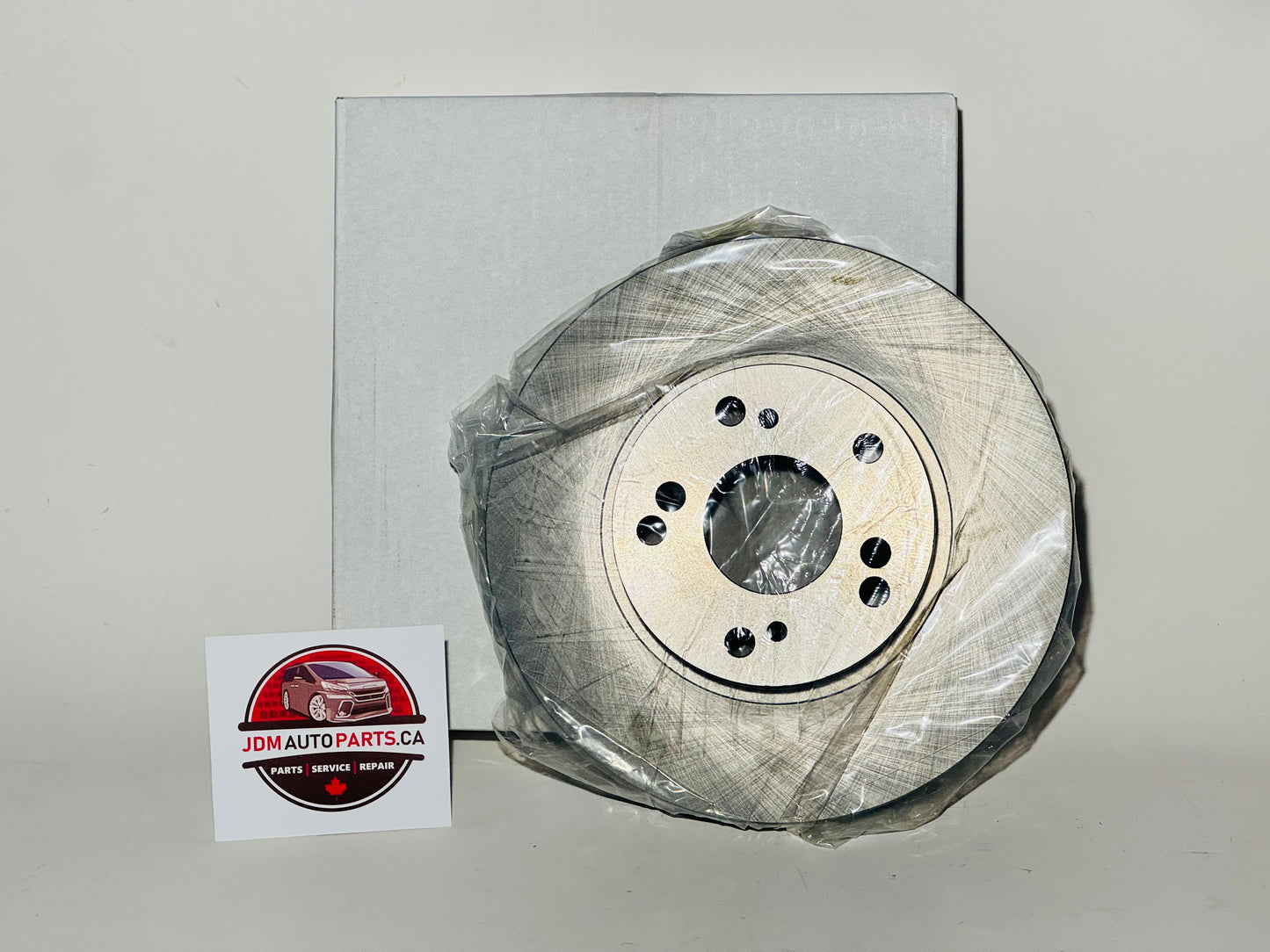 A pair of new aftermarket brake rotors for Honda Stepwgn, packaged in plastic, with a business card showing a logo and contact information.