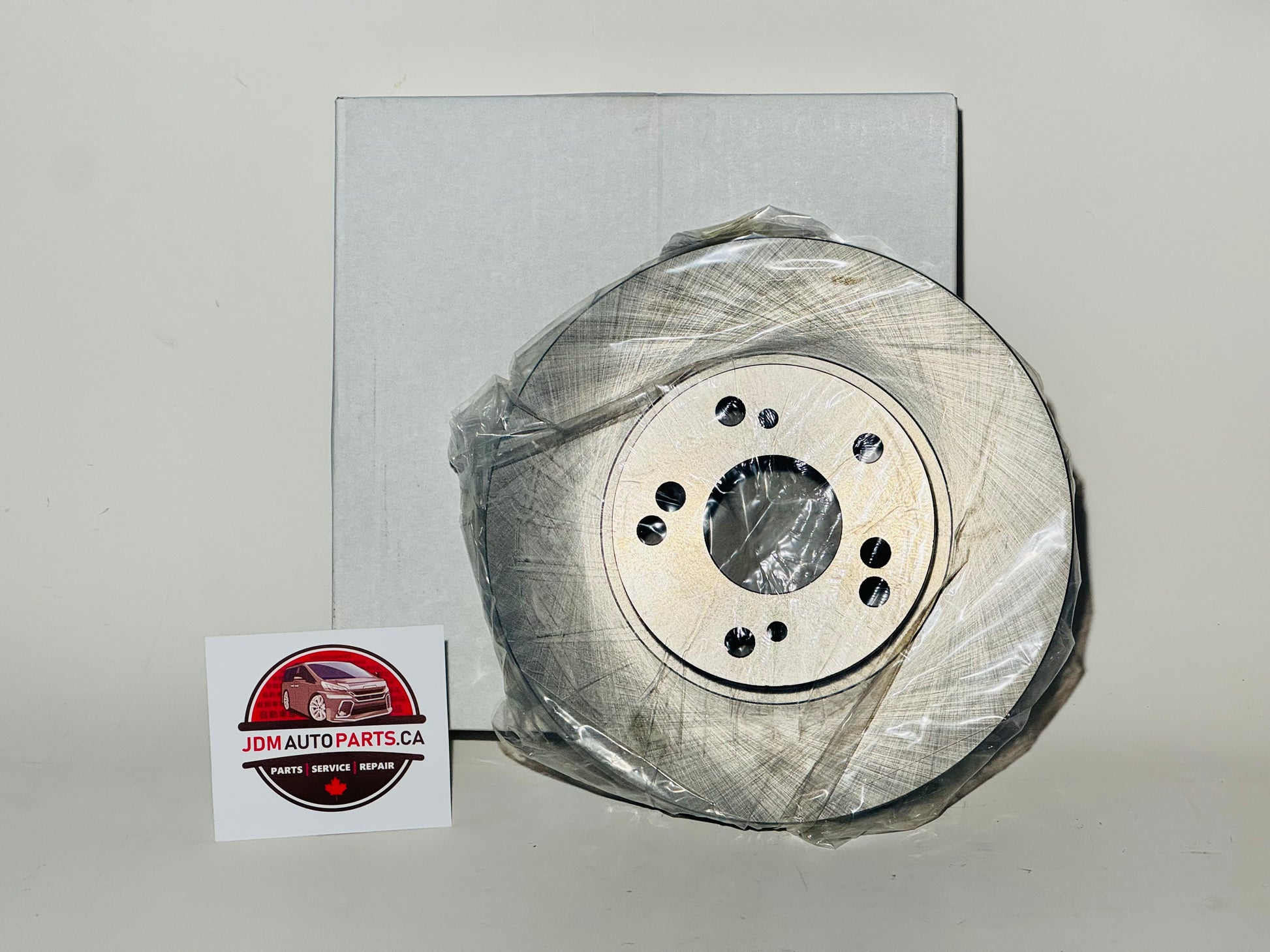 A pair of new aftermarket brake rotors for Honda Stepwgn, packaged in plastic, with a business card showing a logo and contact information.