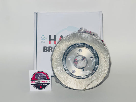 A silver metal brake rotor wrapped in protective plastic, displayed in front of its white branded box and a JDM Autoparts sticker on a light gray background.