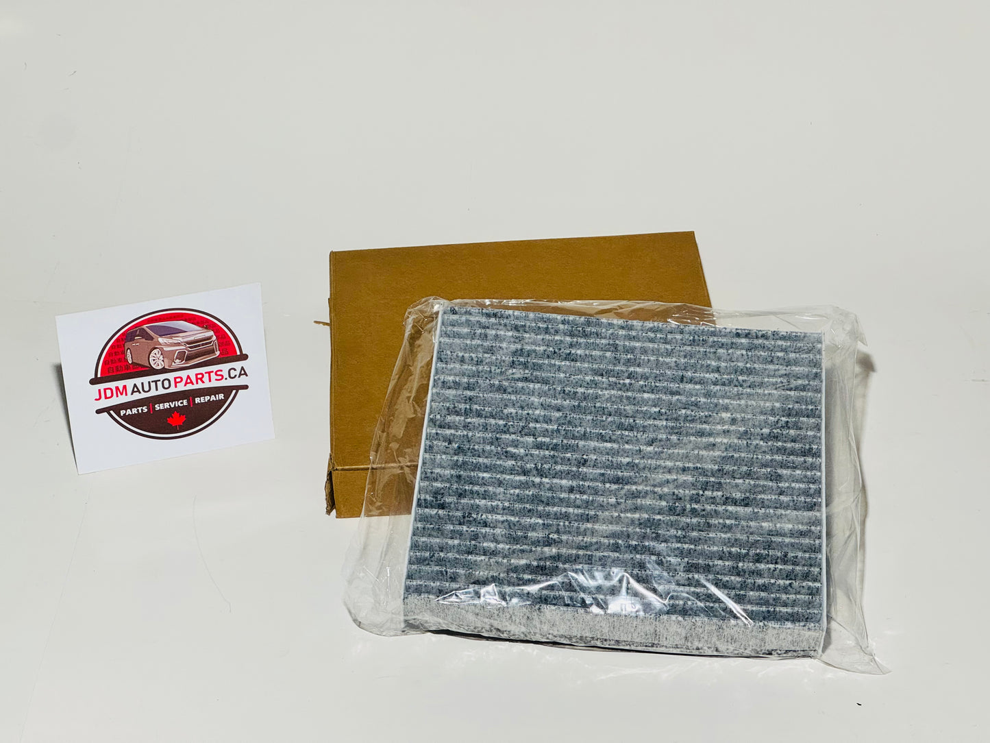 The image shows a cabin air filter for a Toyota Alphard / Vellfire, packaged in a clear plastic bag with a branded cardboard label in the background.