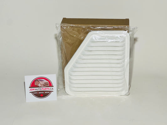 A white engine air filter for Toyota vehicles, placed in front of its packaging, with a Toyota logo sticker next to it.